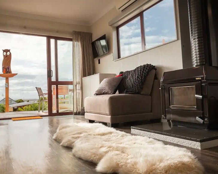 A cosy front room with a wood burning stove looks out onto a deck.