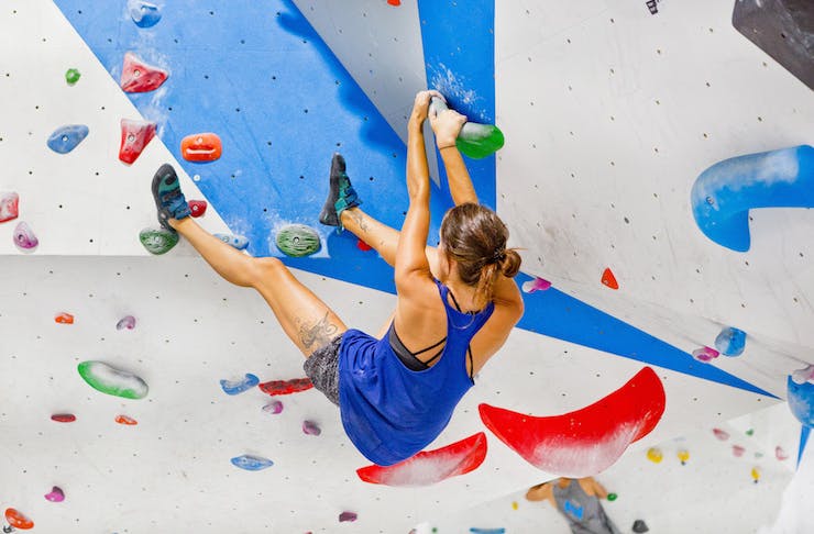a woman rock climbing at an indoor facility