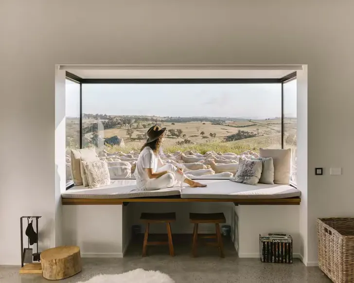 A woman sits in the window admiring the view at Wilga Station Farmers Hut one of the best romantic stays in NSW