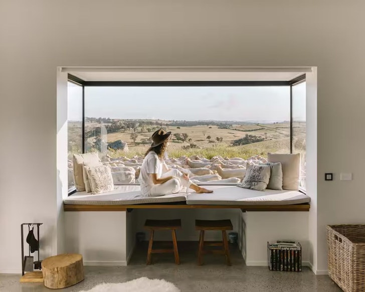 A woman sits in the window admiring the view at Wilga Station Farmers Hut one of the best romantic stays in NSW