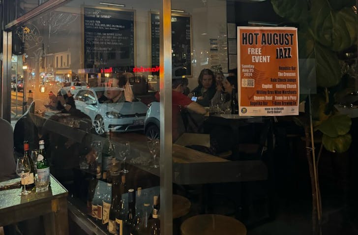 Exterior view of Willing Wine Bar at night, with a warmly lit interior visible through large glass windows