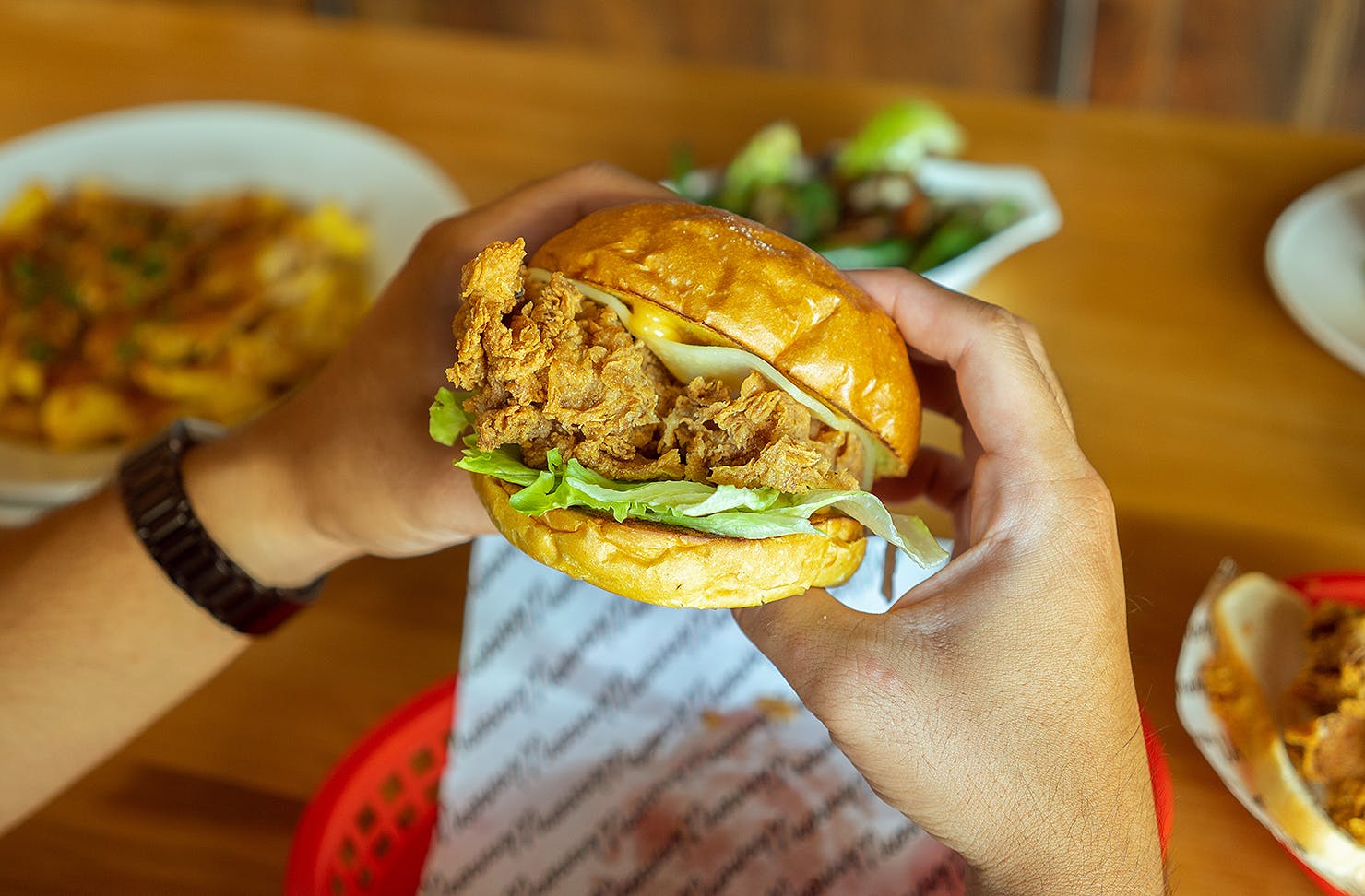 Someone holds a winner winner chicken burger in their hot little hands.
