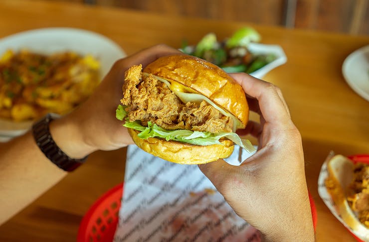 Someone holds a winner winner chicken burger in their hot little hands.
