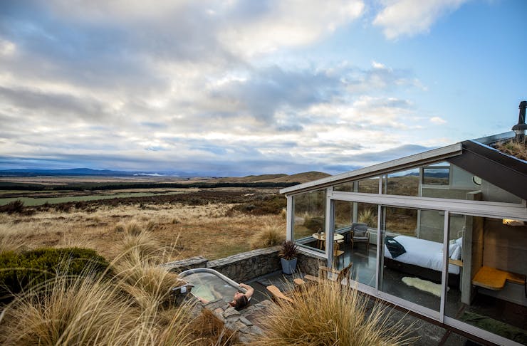 A person soaking in the outdoor hot tub at Skyscape accomodation looking out at views of Mackenzie Country