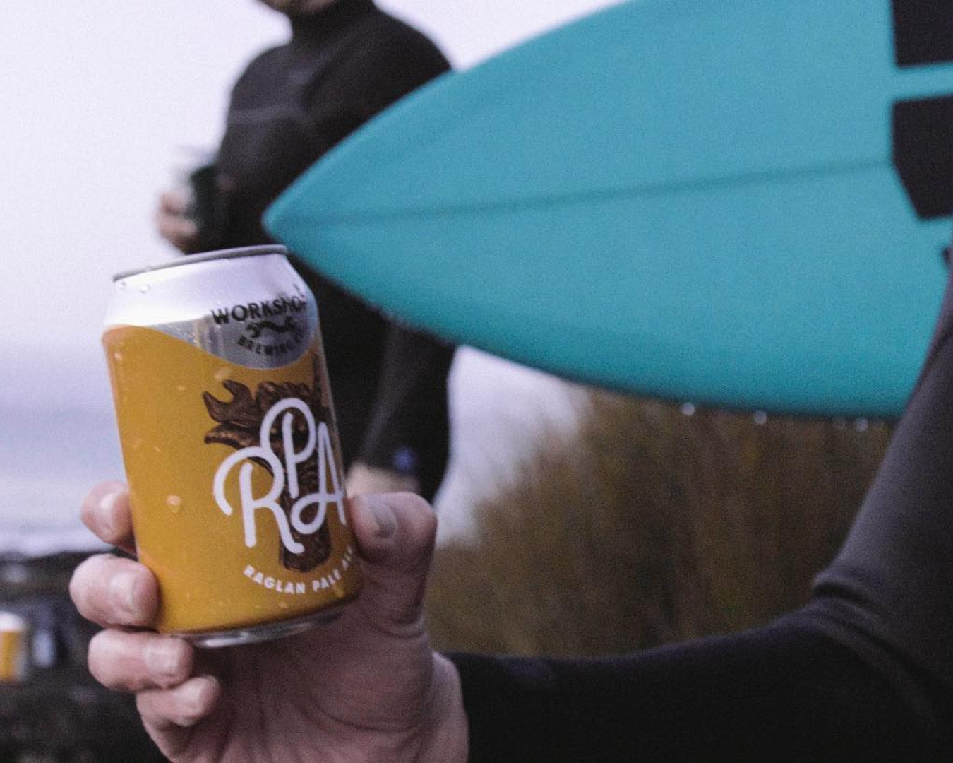 A surfer holding a can of Raglan Pale Ale