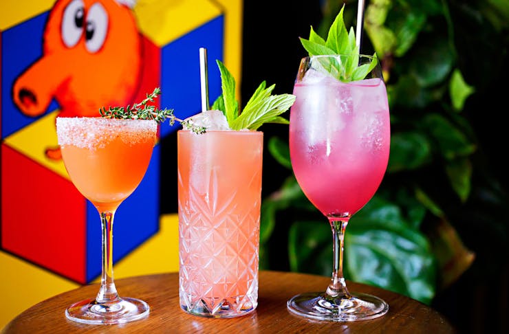 Three colourful cocktails sitting on a bar