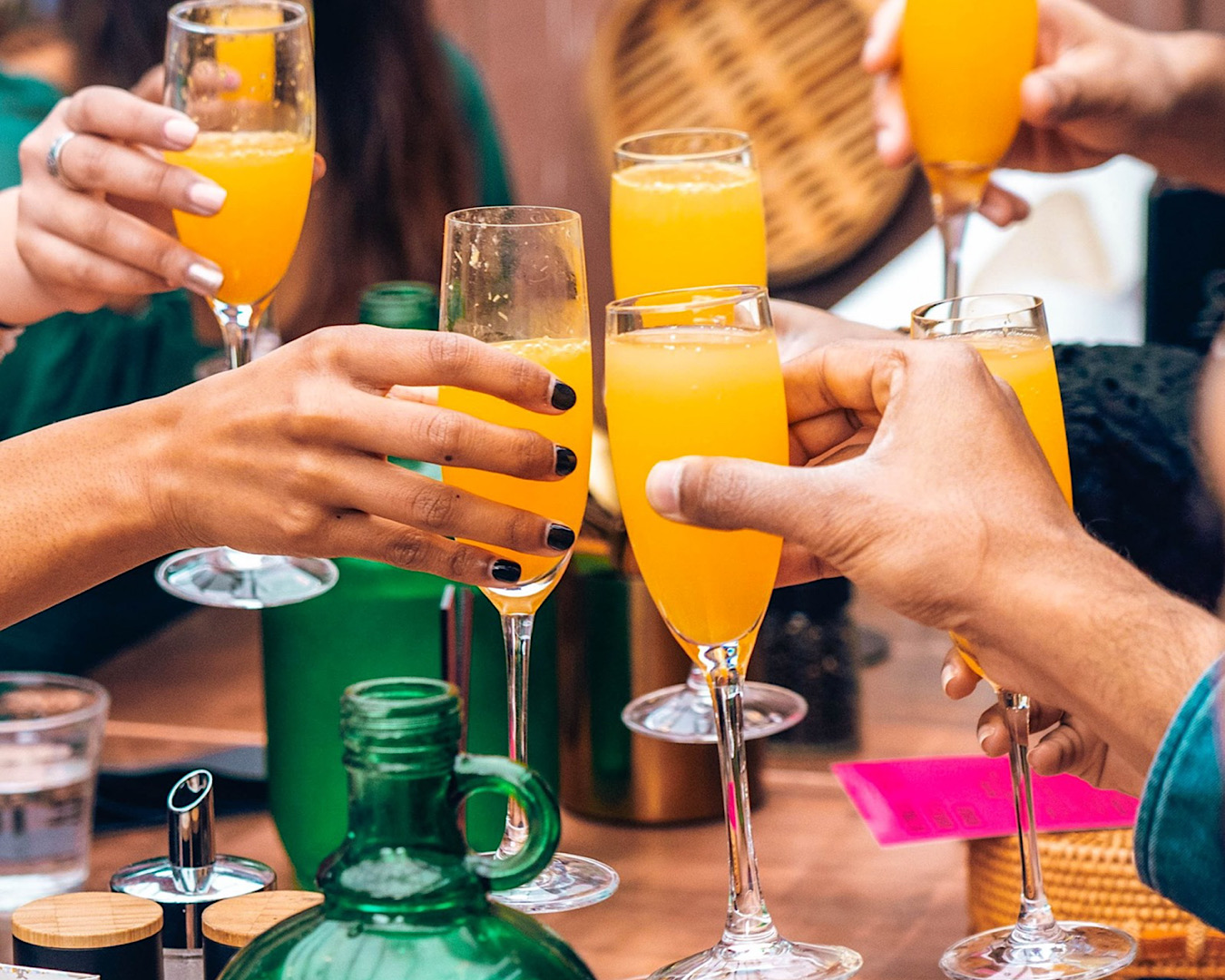 A group of people clink their mimosa flutes together celebrating bottomless brunch at Wu & You, another of the best bottomless brunches in Auckland. 