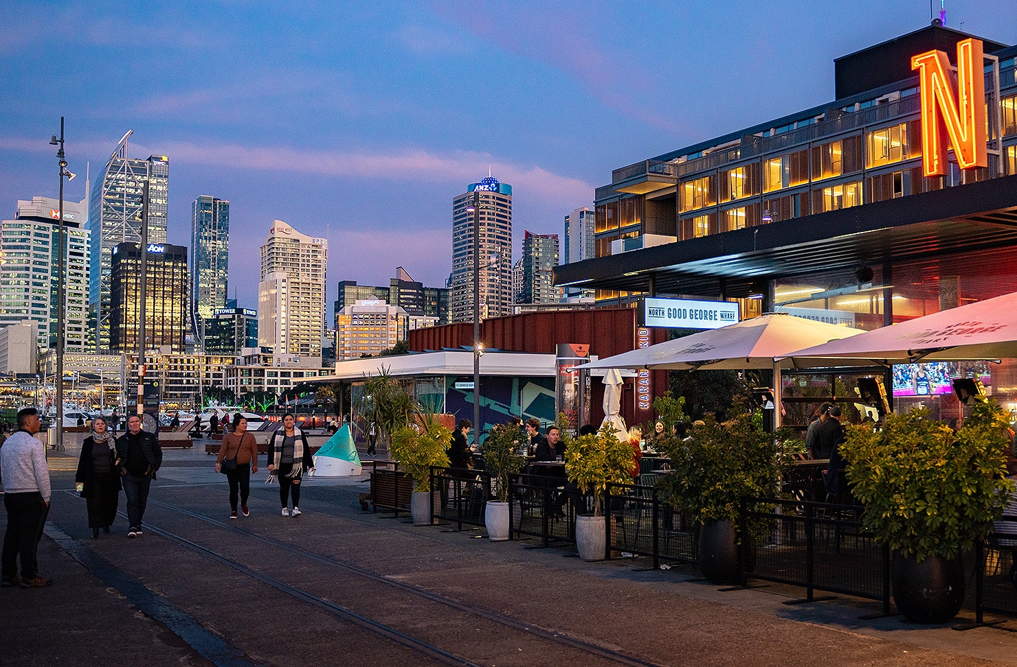 People stroll along the Wynyard Quarter waterfront at dusk.