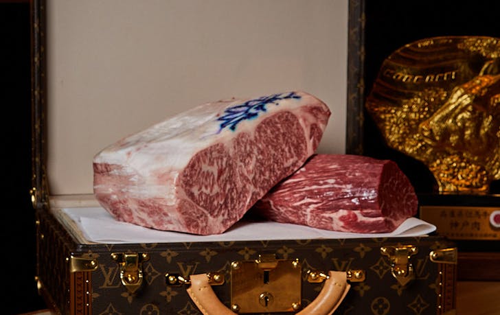 A Louis Vutton suitcase with a large piece of wagyu beef on it. 
