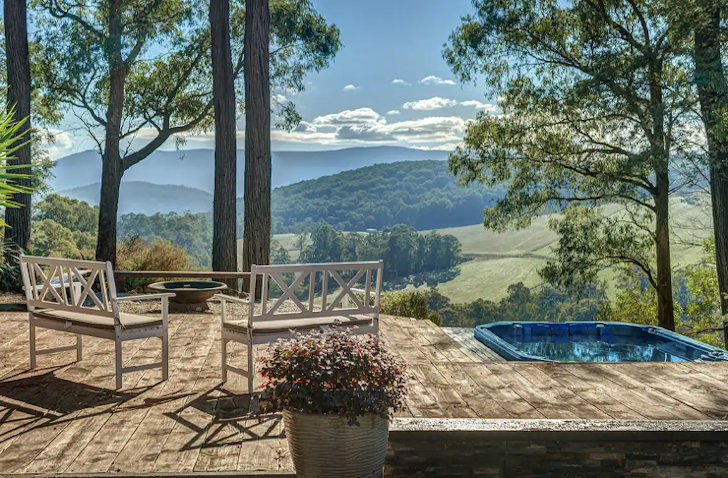 A blue-coloured spa sits on the corner of a timber deck.
