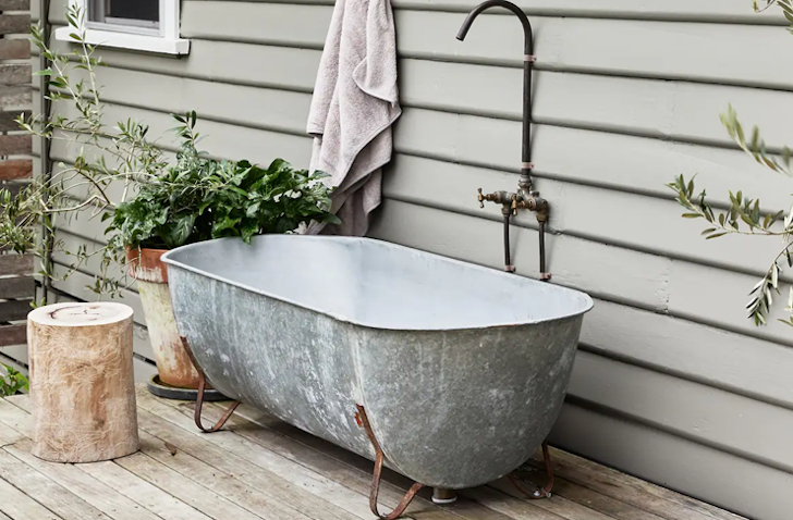 A metal-style bath sits outside on a timber veranda.  