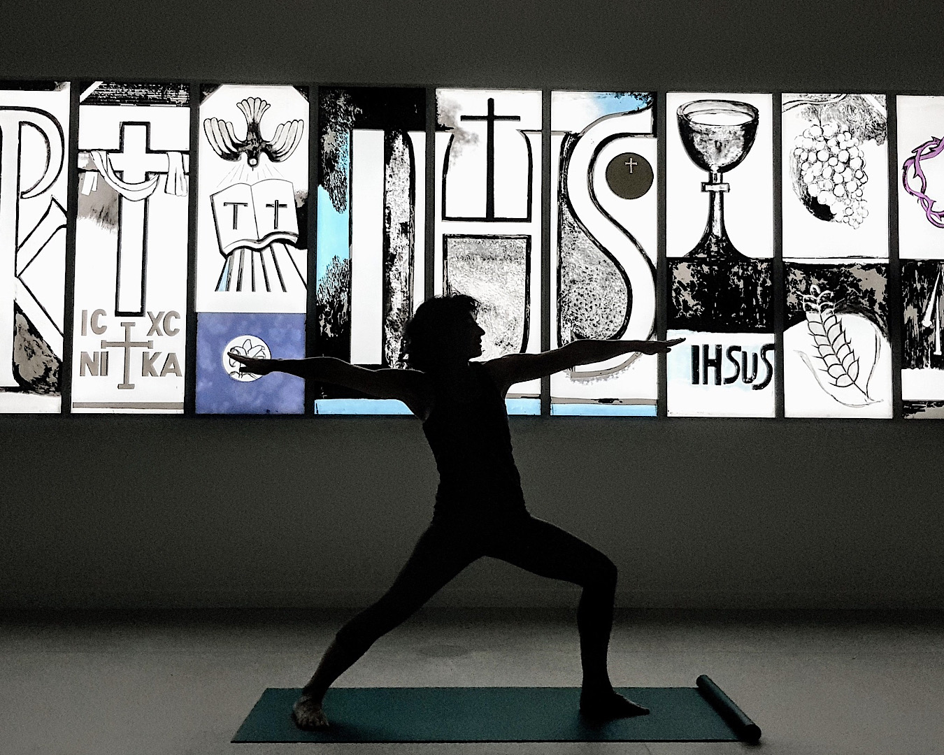 A silhouette of someone doing yoga in front of a lit stained glass-style piece of artwork at the Auckland Art Gallery, definitely one of the best things to do in Auckland. 
