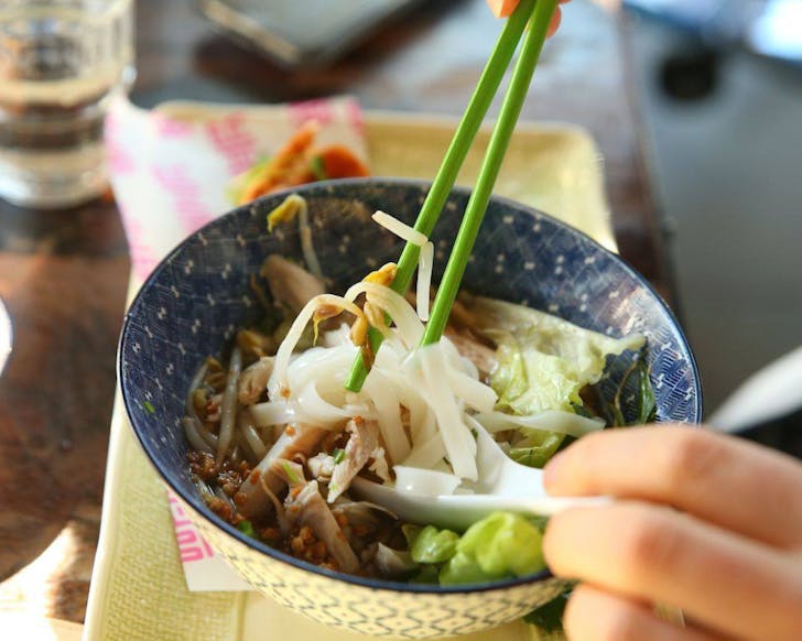 Someone gets stuck into a steaming hot bowl of pho at You Hanoi Me. 