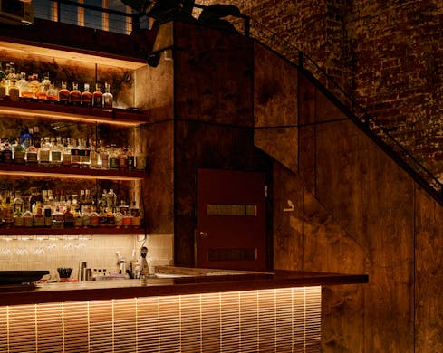 The Young Hearts Bar lit up at night with bottles on the shelves.