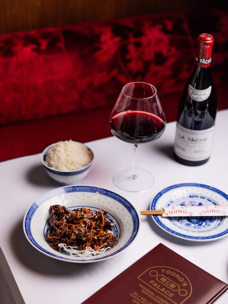 A dish of noodles and beef on a table with wine at Young's Palace, Potts Point