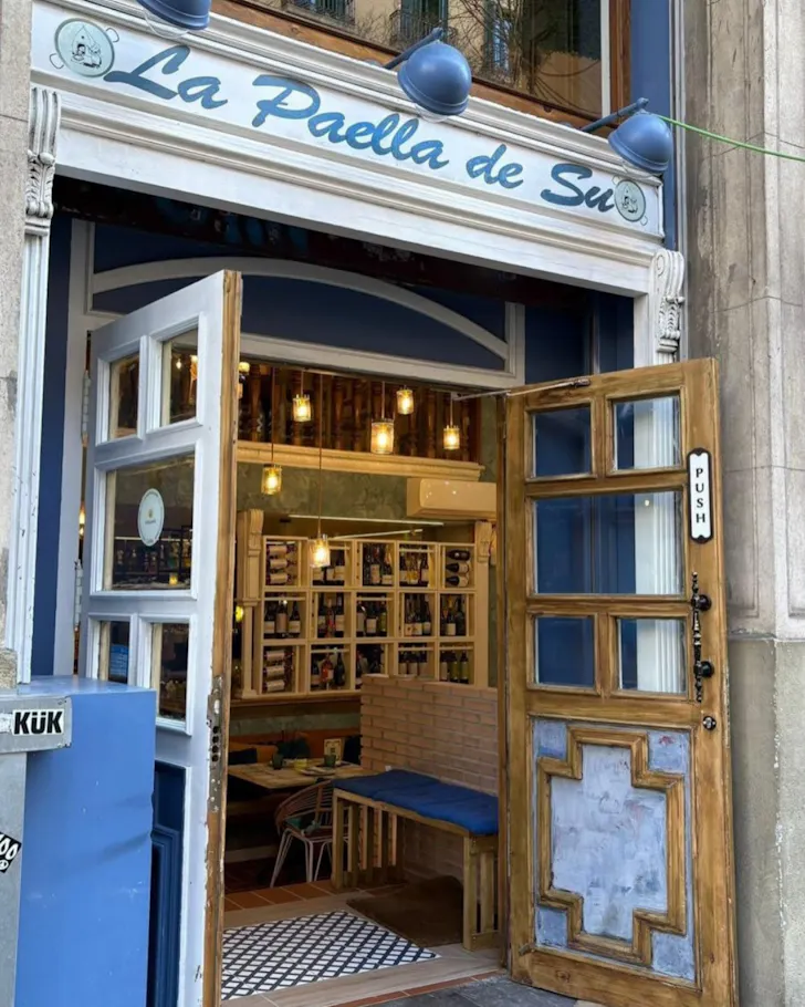The blue-and-white storefront at La Paella de Su leads into a vintage-style interior.