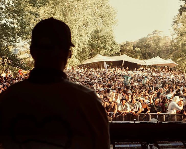 A shadowed DJ plays in front of an energetic crowd under the sun at Northern Bassâ Jungle Stage.