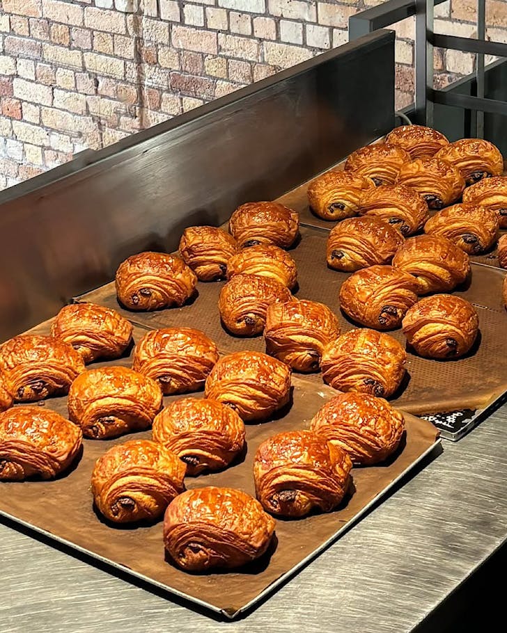 Freshly baked croissants line a metal tray to cool off at Daily Bread.