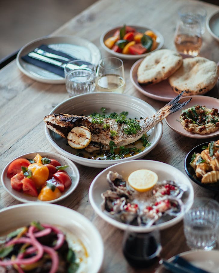 Plates of delicious food, including grilled fish, fresh tomatoes and fresh oysters at Odettes.