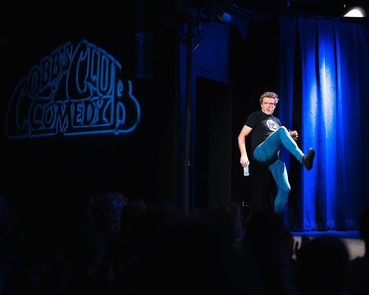 Derby performs on a dark stage at Cobb's Comedy Club.