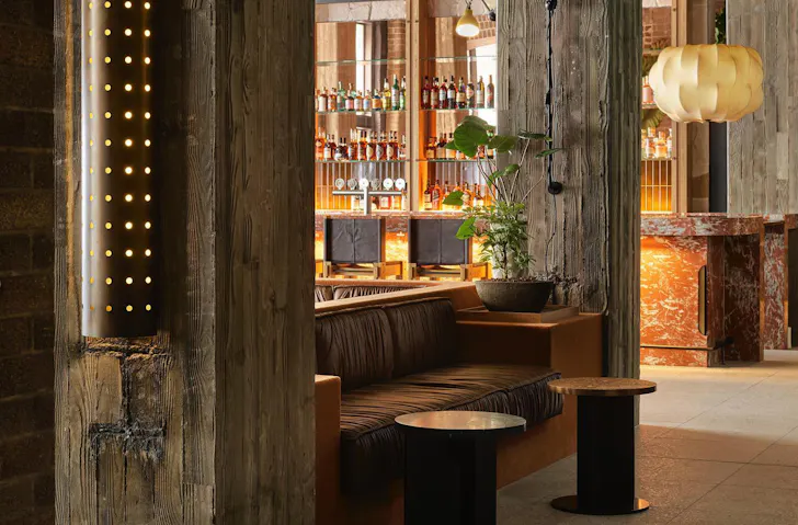 Bar tables beside a plush leather booth at Ace Hotel Sydney