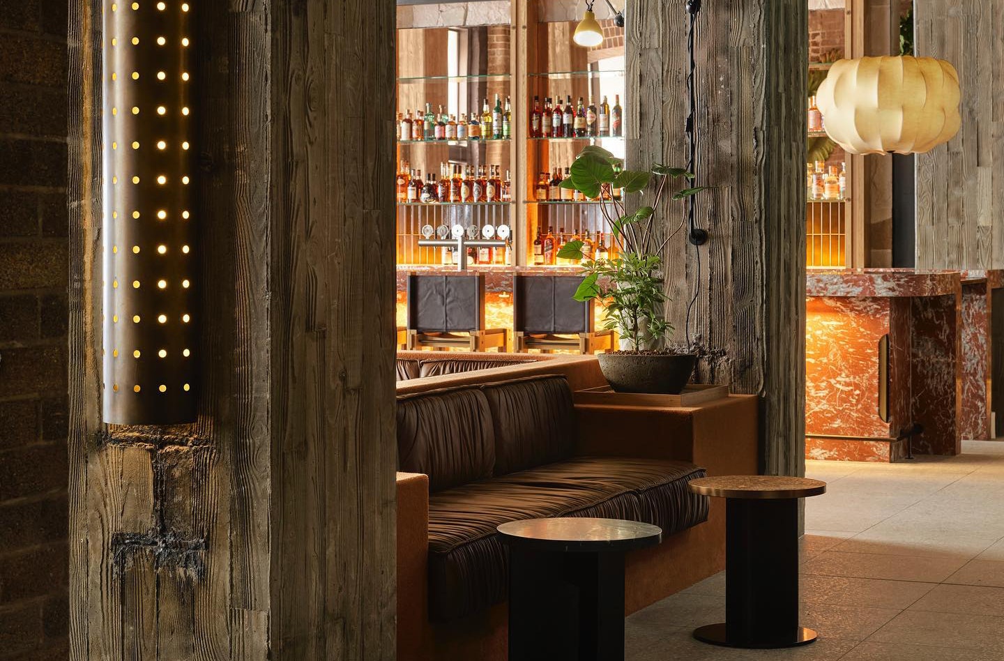 Bar tables beside a plush leather booth at Ace Hotel Sydney