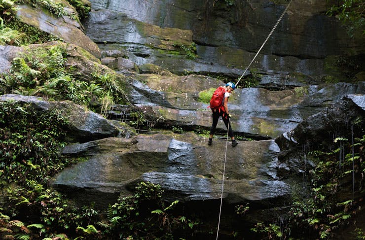 A woman abseiling down a waterfall in NSW. 