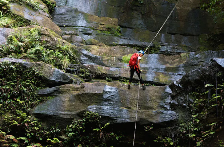 A woman abseiling down a waterfall in NSW. 