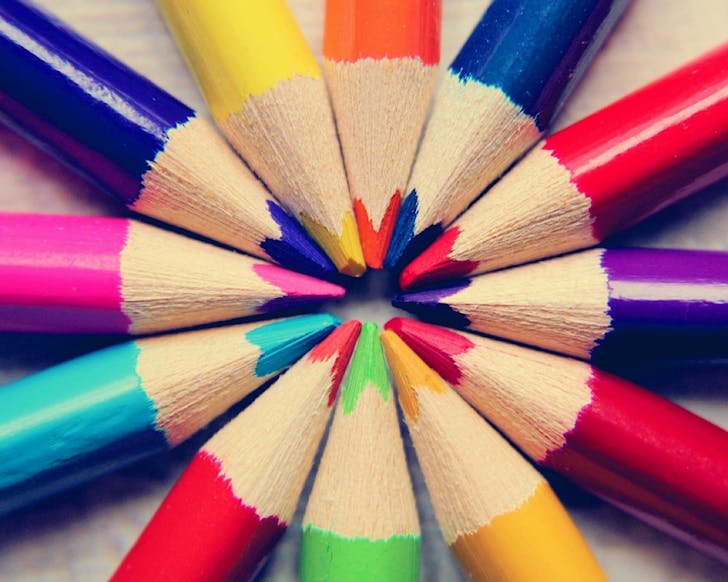 A close-up shot of colourful pencils arranged in a rainbow circle with the points touching.