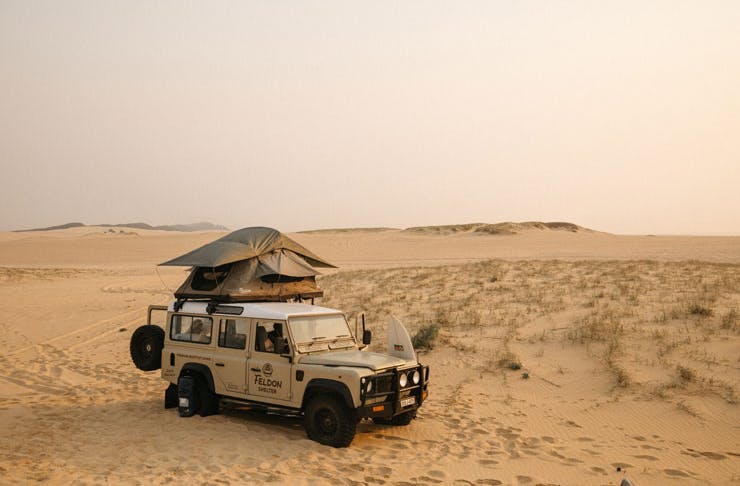 A four wheel drive parked for camping on sand dunes. 