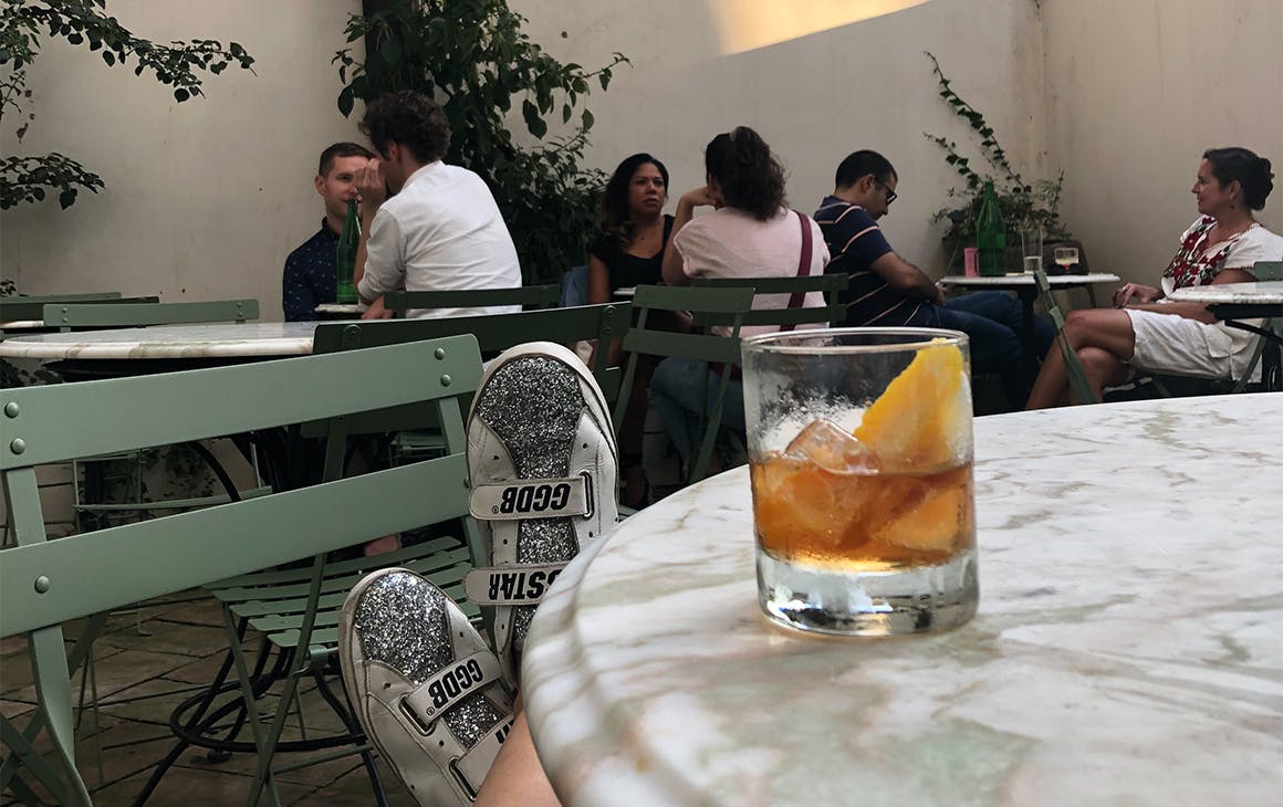 a small courtyard bar, a drink rests on a table in front of the camera