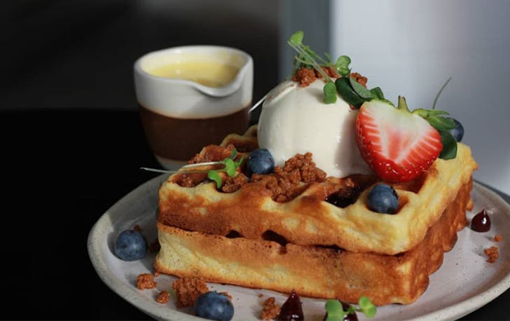 Two waffles topped with ice cream and berries