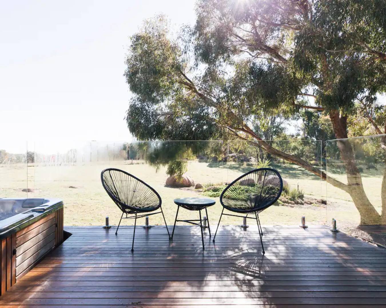 two chairs on deck overlooking green paddocks and trees
