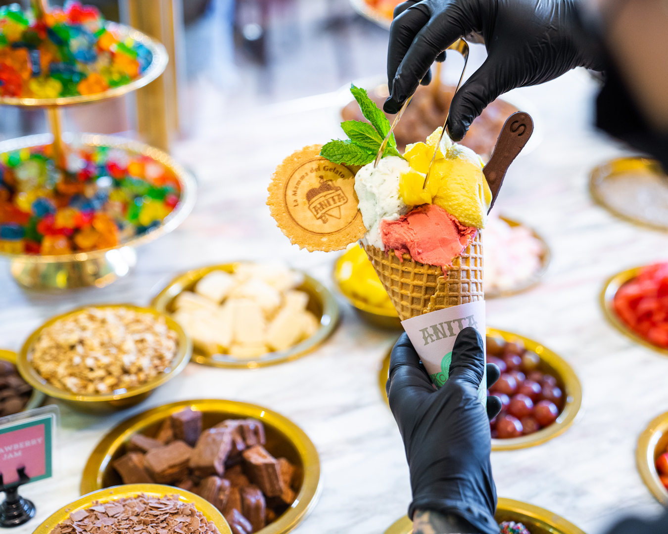 A colourful scoop of ice cream held above various toppings.