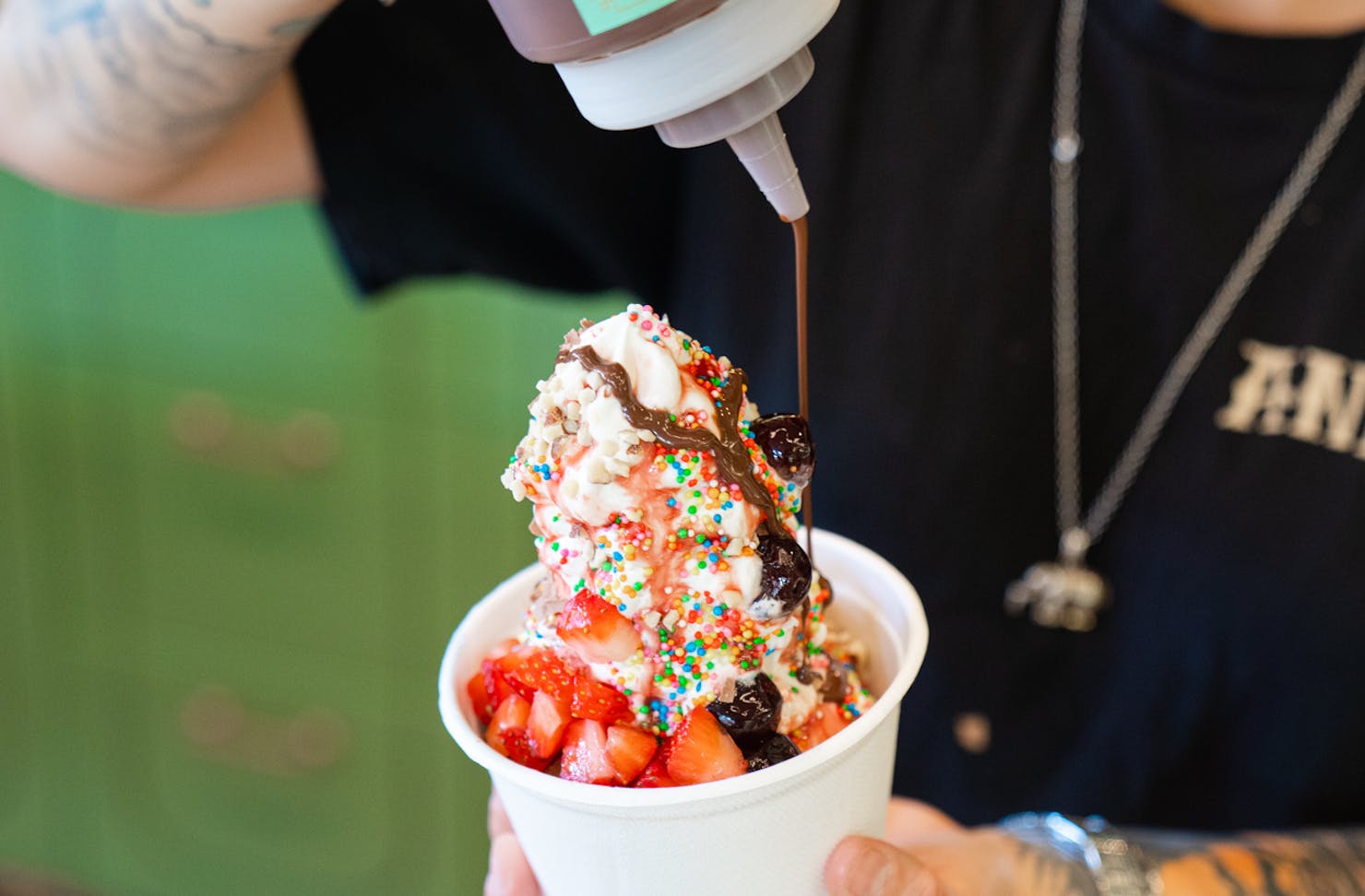 Chocolate sauce being added to an ice cream sundae.