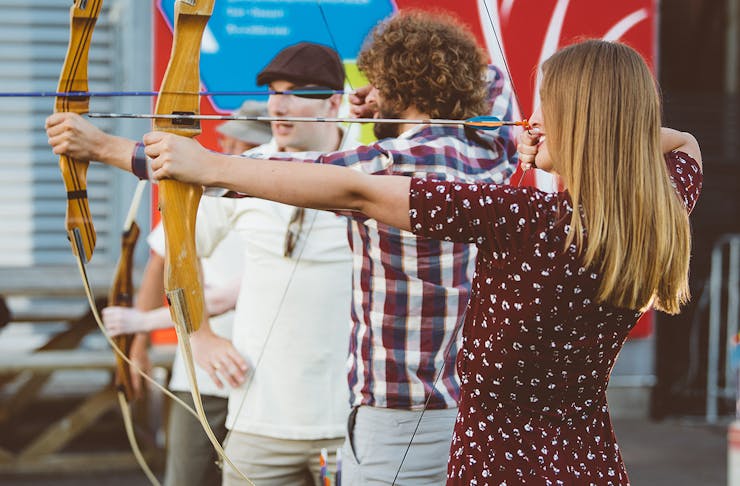 A girl lines up a shot with a bow and arrow at anti valentine's day
