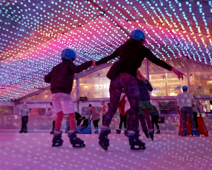Peopl enjoy the Aotea ice rink under purple and blue lights.