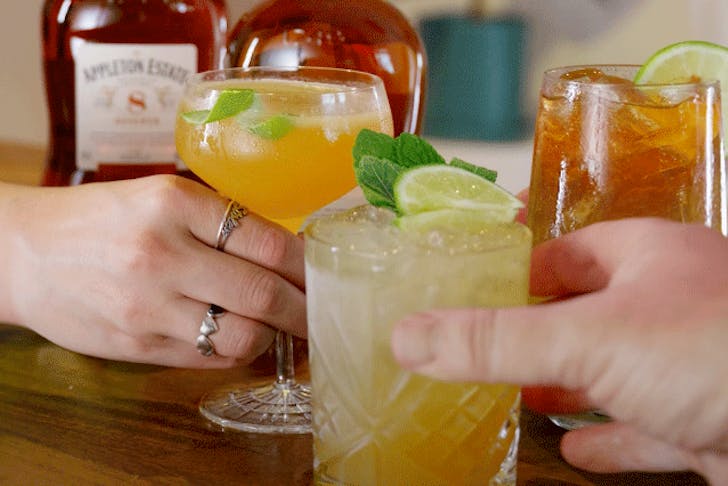 Hands reaching for 3 cocktails made with Appleton Estate rum