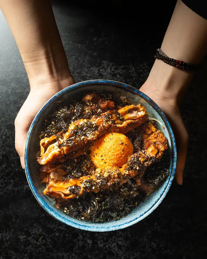 Two hands hold a loaded donburi bowl from Astro in Barangaroo