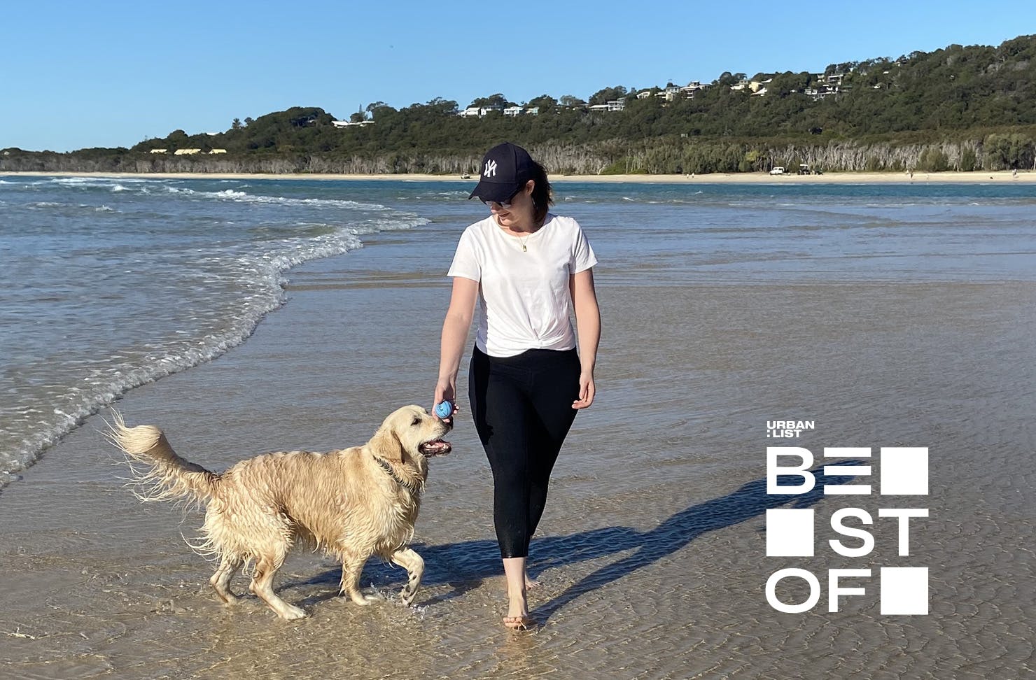 Woman plays with her gold retriever at the beach 