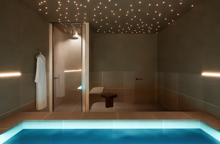 Render of AURA Spa & Bathhouse's float therapy room featuring a glowing float pool, star-like ceiling lights, walk-in shower and calming minimalist interiors.