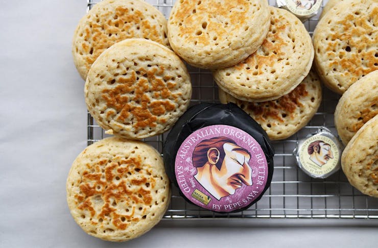 a pile of crumpets on a tray with packages of butter