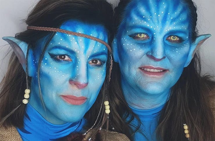 Two girls with painted faces looking like characters from Avatar.