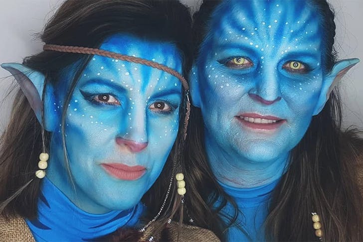 Two girls with painted faces looking like characters from Avatar.