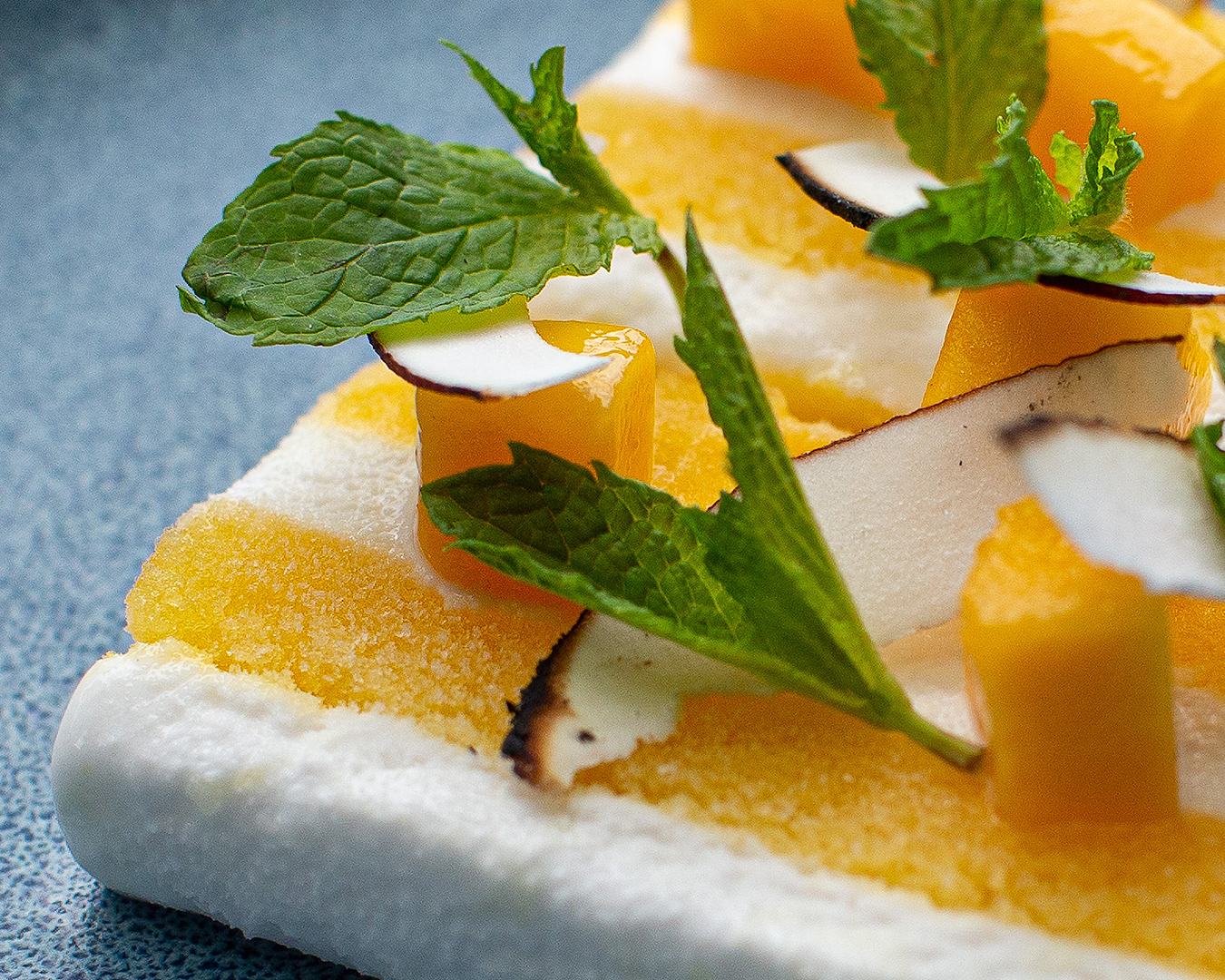 The taste bud tingling Yuzu slice, a bright yellow and white frozen dessert with leaves delicately placed on top.