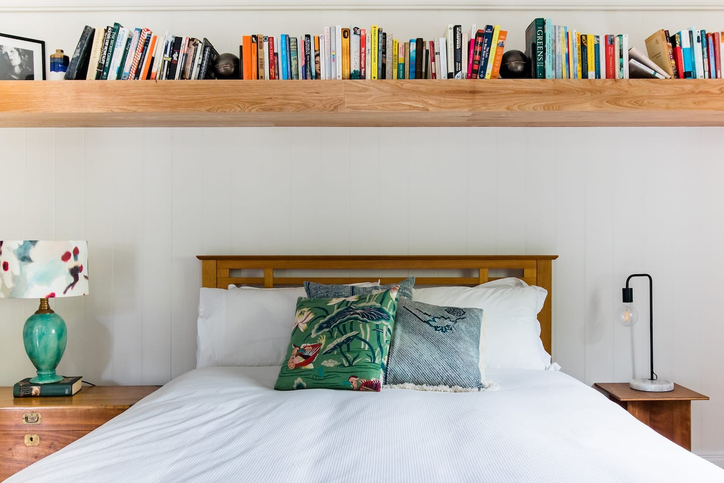 a bed under a shelf of books