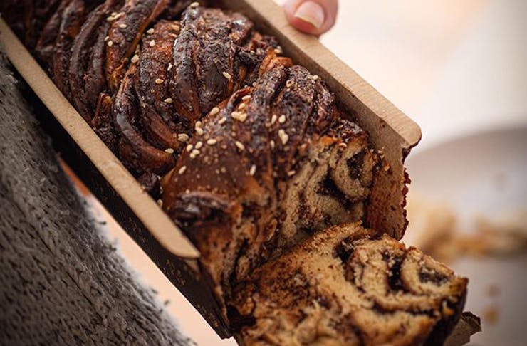 A cross section of a chocolatey babka being held by two hands.