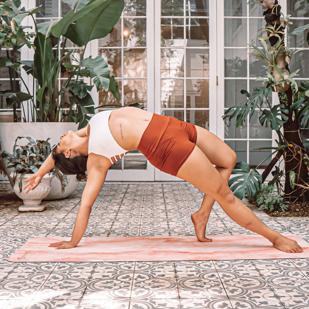 a woman doing yoga on a colourful mat on an outdoor patio