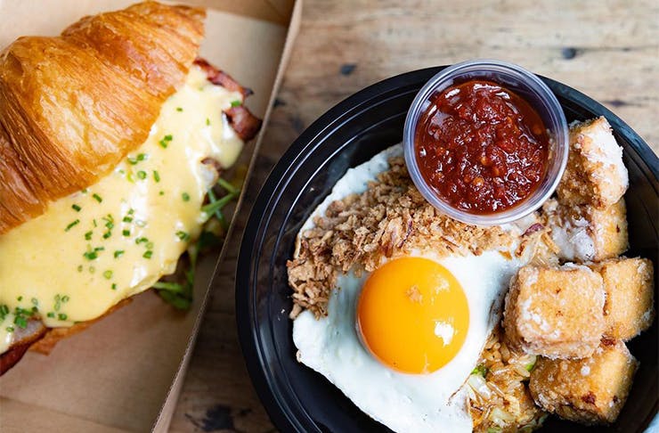 a croissant and egg dish in takeaway containers