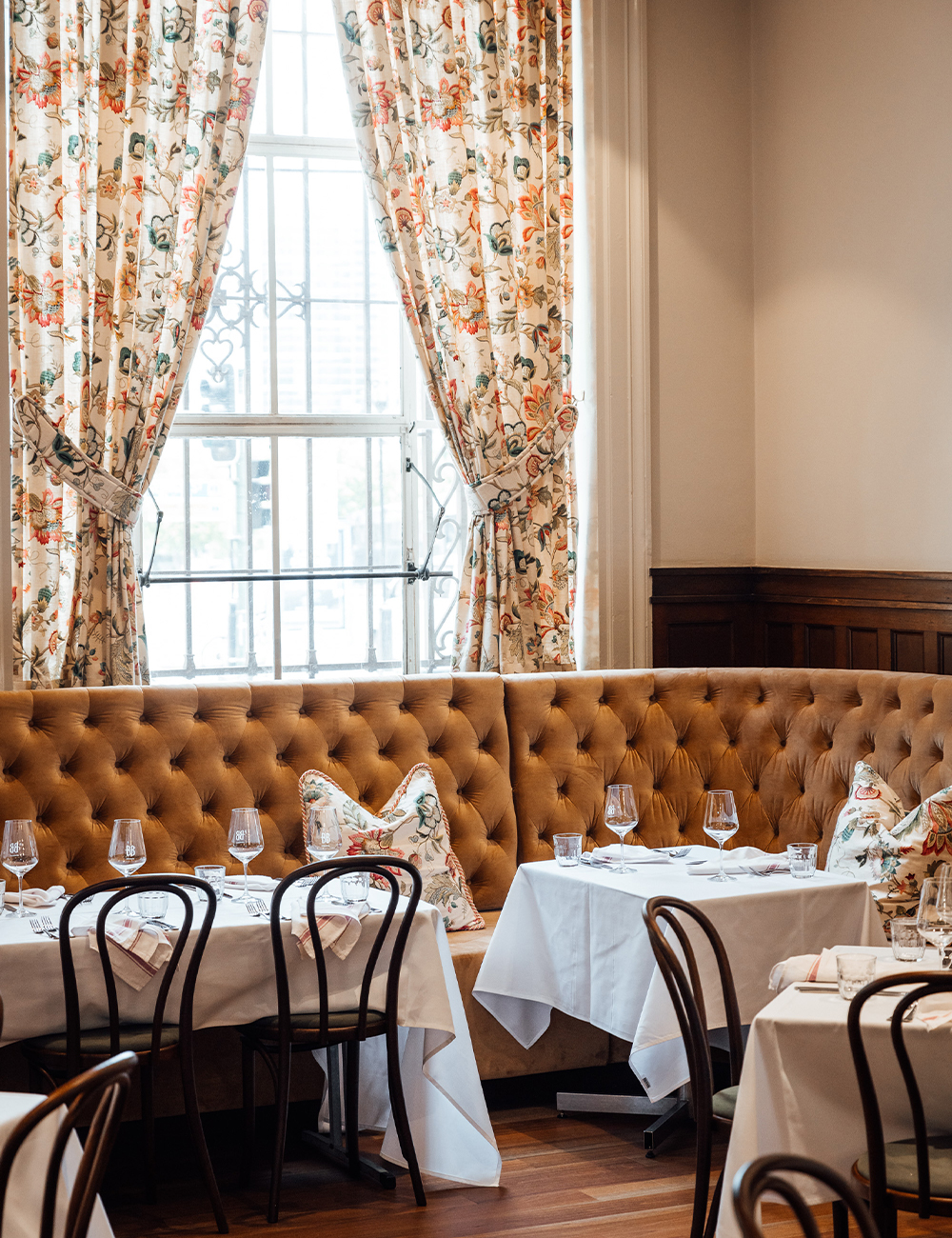 a table underneath floral curtained windows